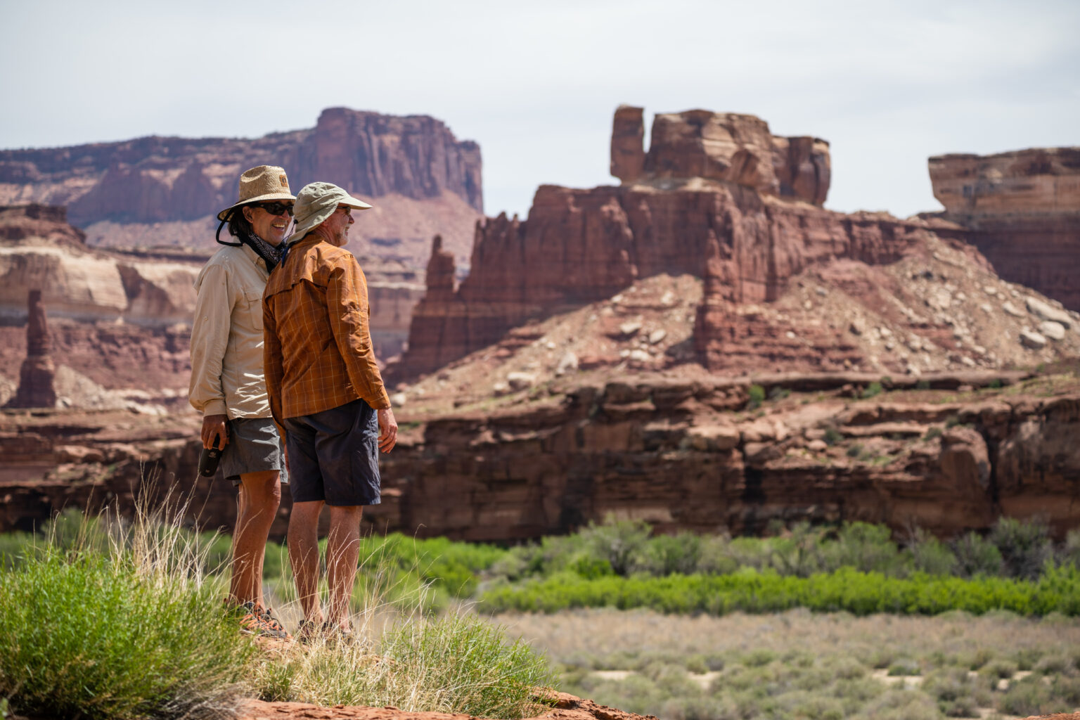 Two men wearing wide-brimmed sun hats in a dramatic desert setting.