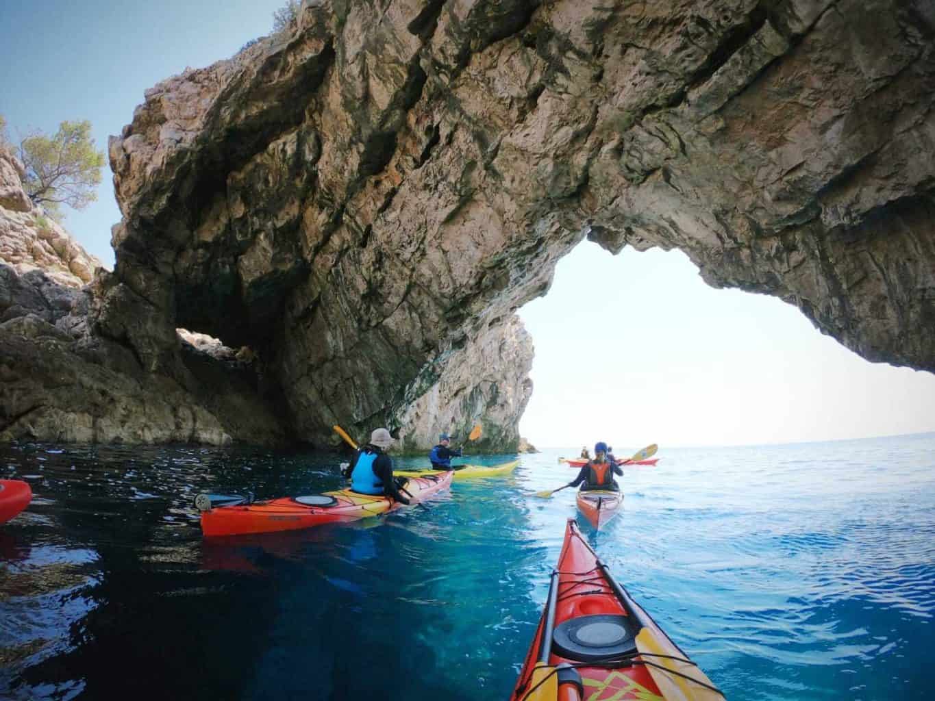 Sea kayakers paddle under an arch near Croatia