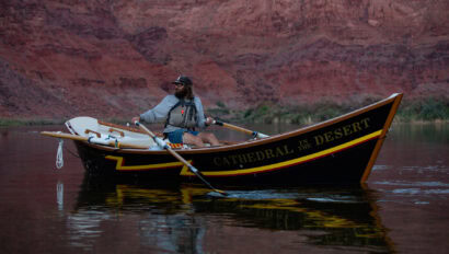 A river guides rows a wooden dory named Cathedral in the Desert