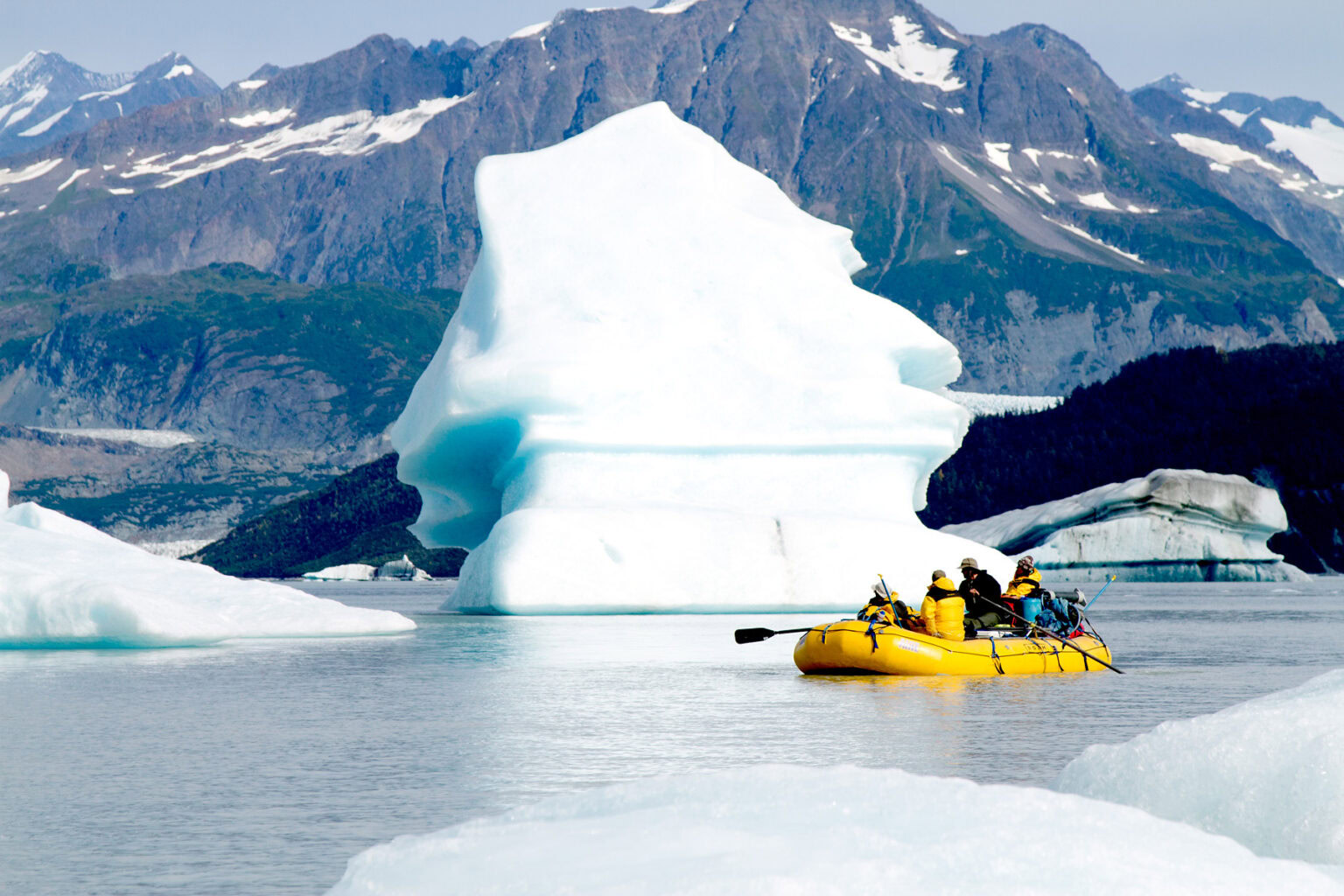 A raft floats by an iceberg on the Tatshenshini River