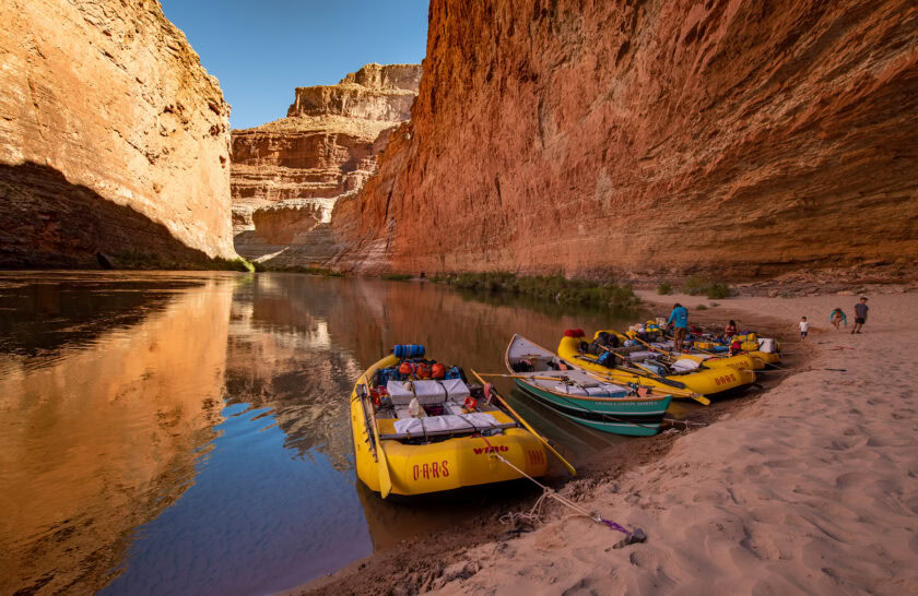 OARS rafts and dory moored at a sandy beach at the mouth of Redwall Cavern in Grand Canyon