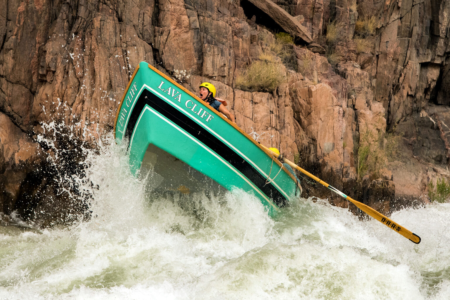 OARS dory Lava Cliff launches into the air with screaming guest hanging on tight in big rapid in Grand Canyon