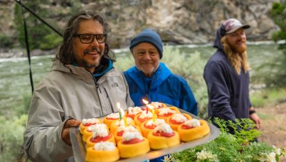 A man shows off a pound cake dessert with strawberry rhubarb sauce and whip cream