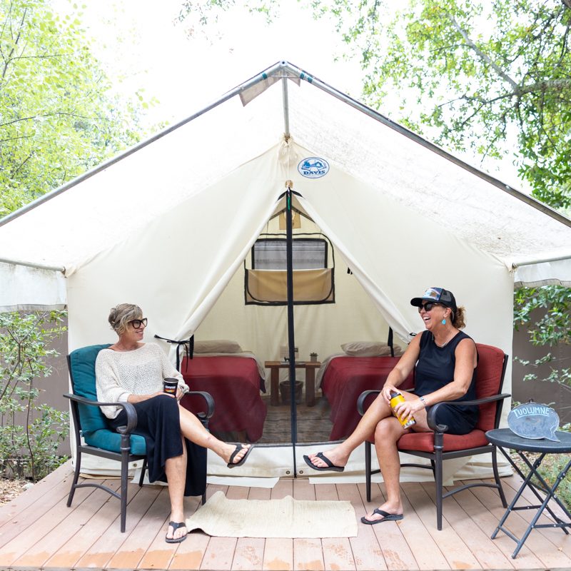 Two women enjoy the deck of a platform tent at the OARS American River Outpost