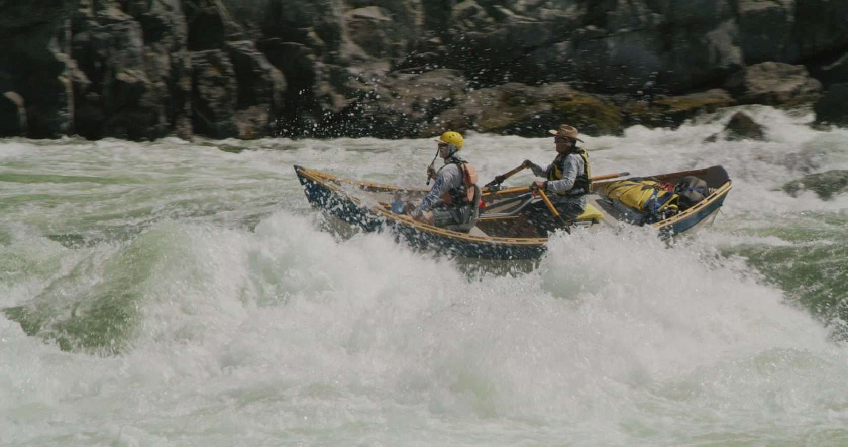 A guide running Wild Sheep Rapid on the Snake River in his dory with a passenger. 