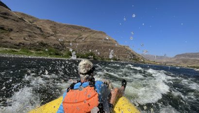 A guest on an OARS rafting trip rides through a rapid on the Snake River